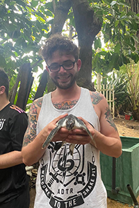 PhD student with ECORSIC, Dylan Ashby, holding a turtle.